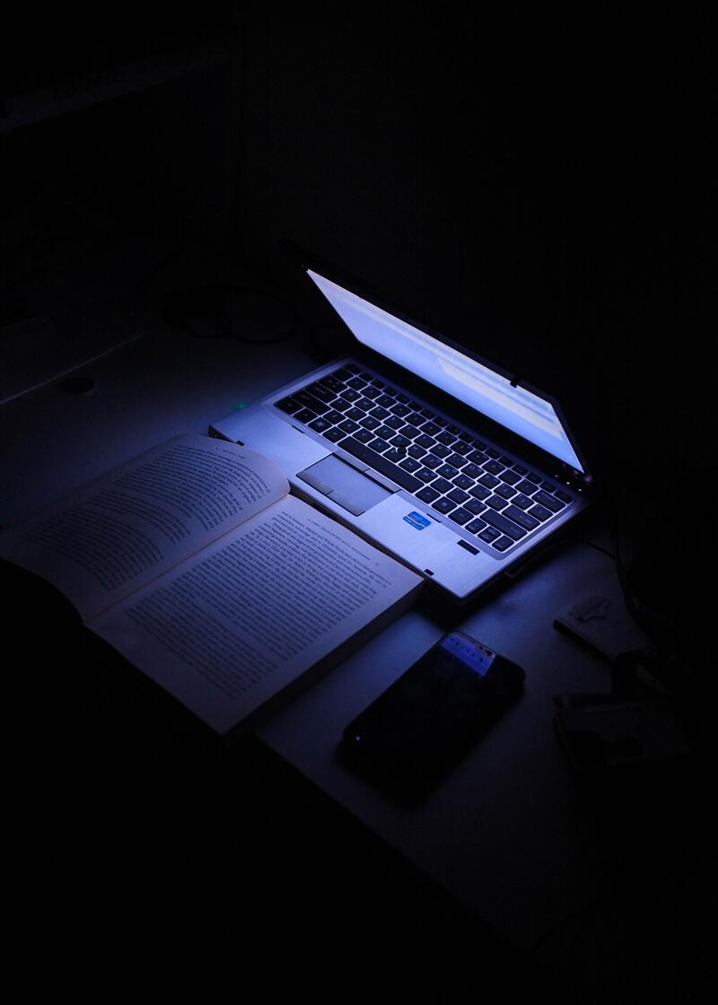 dator som lyser upp en bok i mörkret 